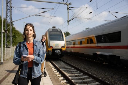 Foto einer jungen Frau am Bahnsteig, hinter ihr ein Zug