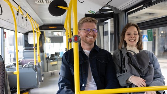 Foto einer jungen Frau und eines jungen Mannes, die lachend im Bus sitzen