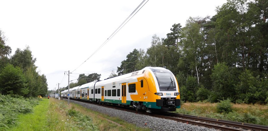 Das Foto zeigt den Desiro HC-Zug von außen auf einer Bahnstrecke durch die Natur.