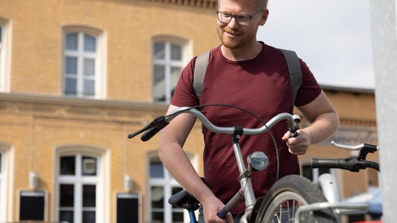 Fahrradfahrer stellt Fahrrad in einer B+R-Anlage am Bahnhof ab